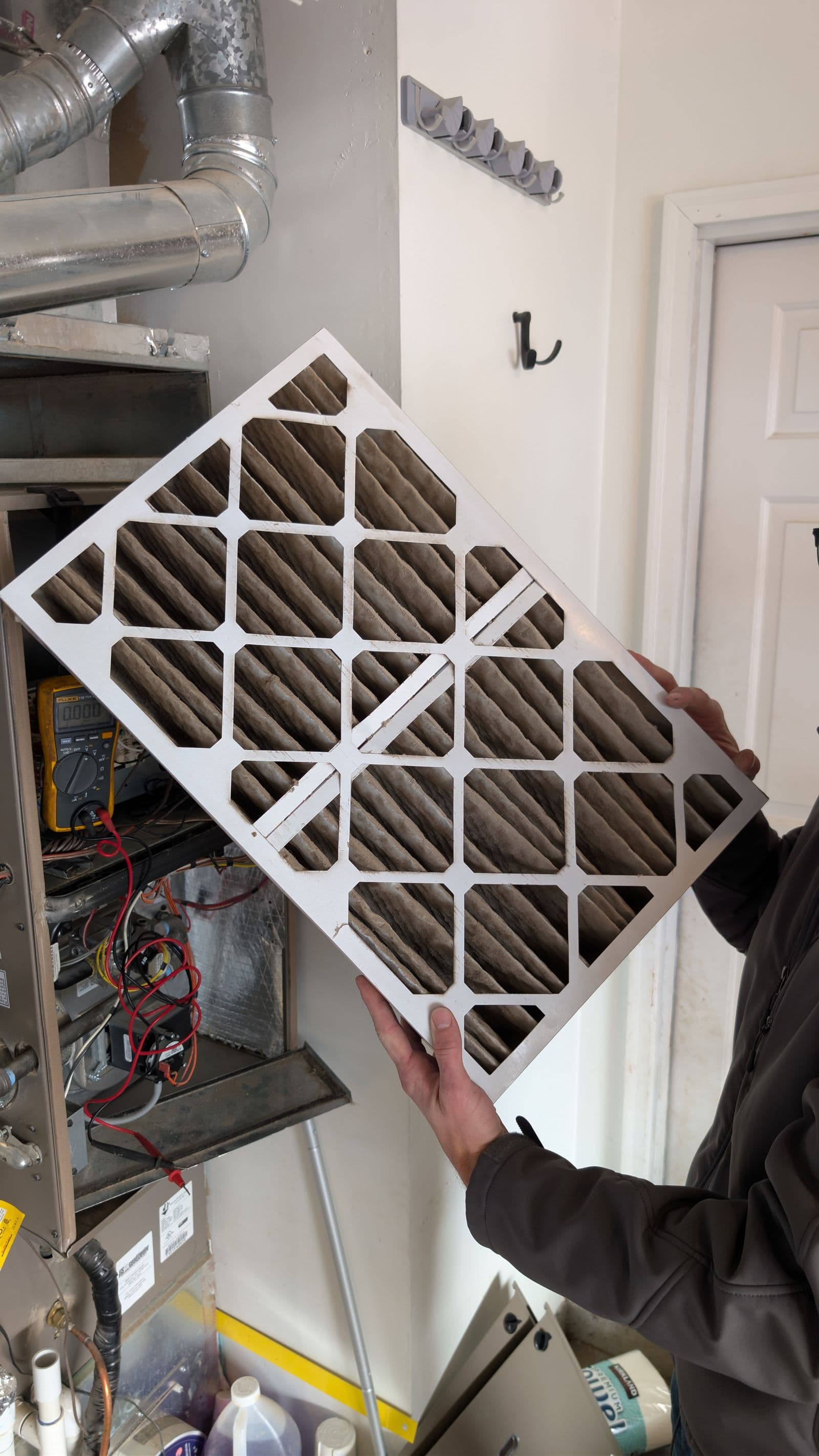 HVAC technician holding dirty air filter during maintenance service in Meridian