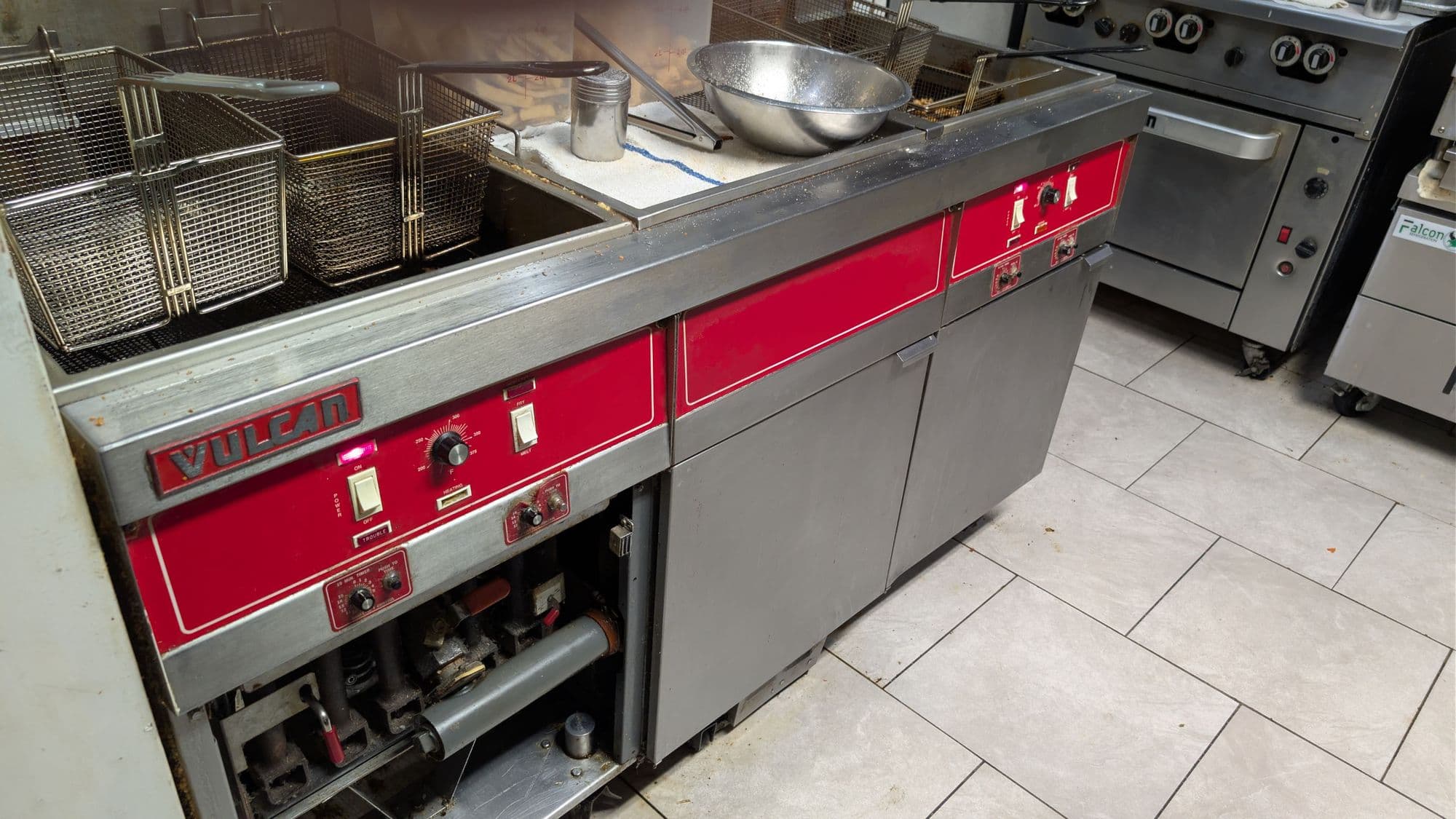Bank of electric fryers with baskets on a restaurant cook line, next to a range