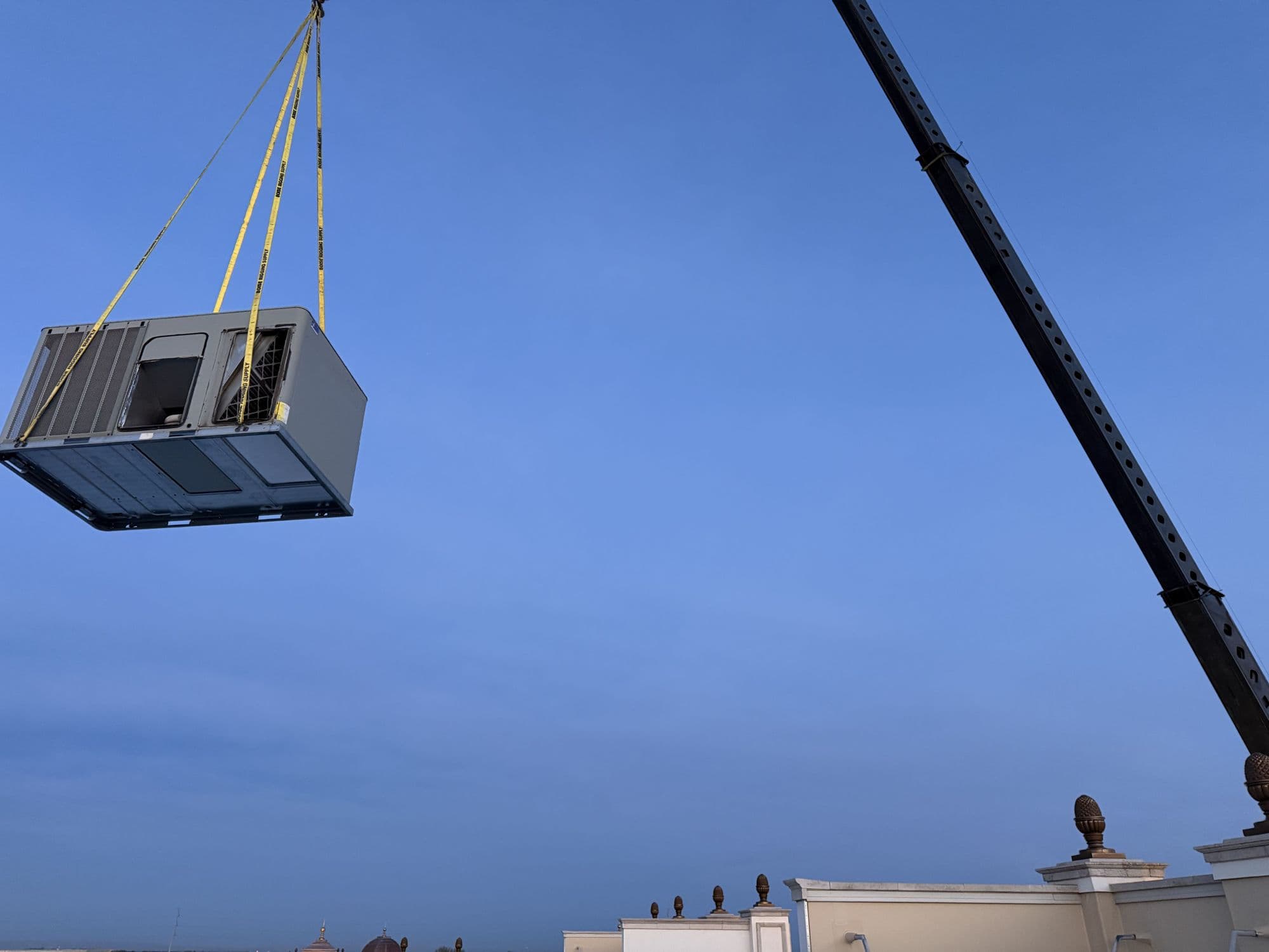 Rooftop unit lifted by crane during a commercial replacement