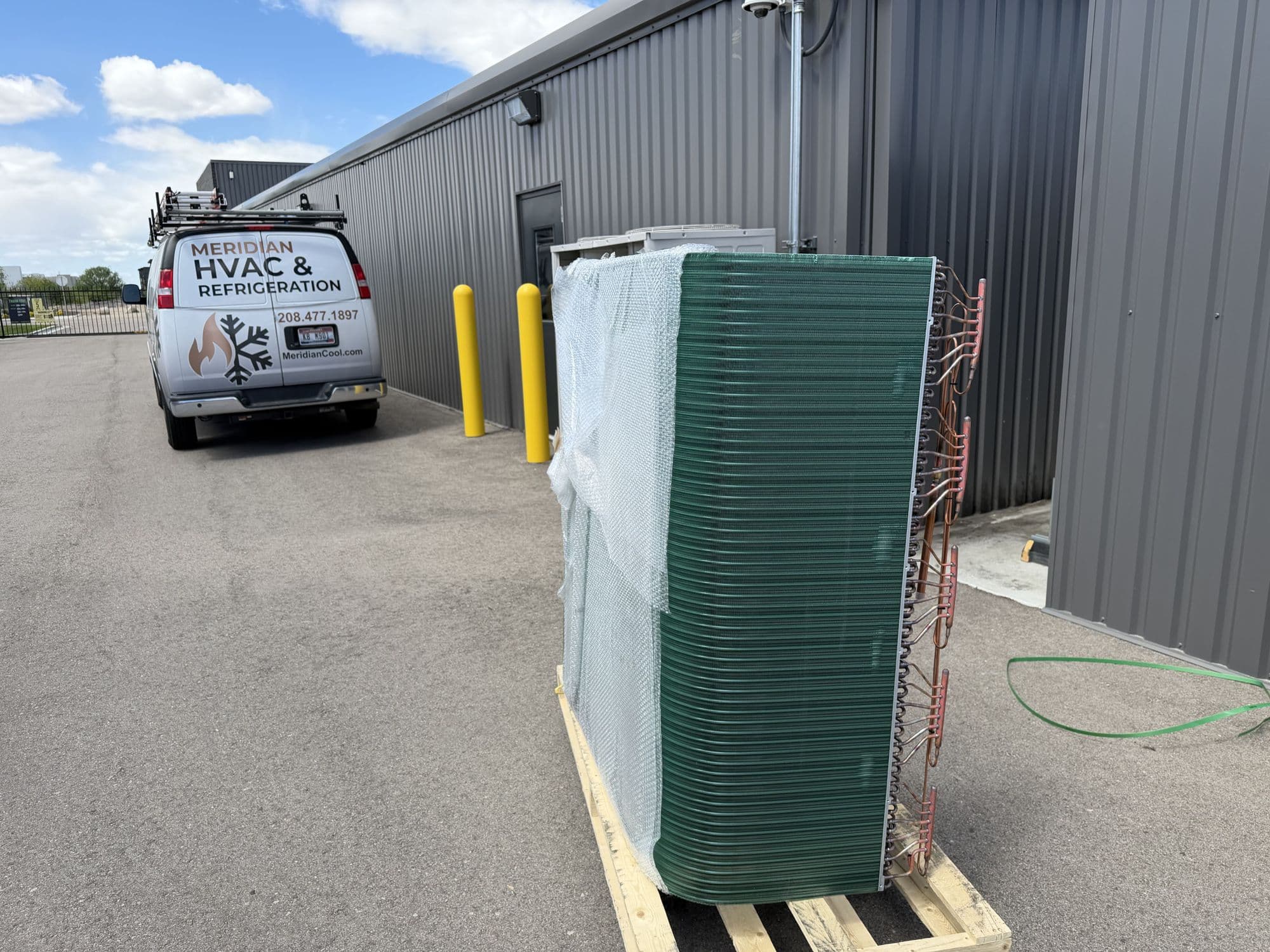 Meridian HVAC & Refrigeration service van at a commercial building with a new condenser coil on site