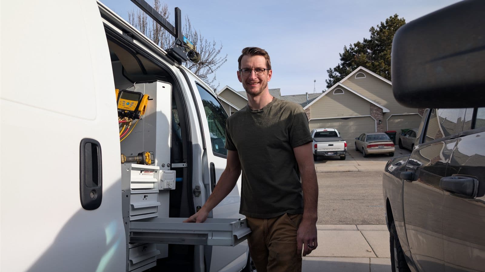 Friendly Meridian HVAC technician in front of a service van